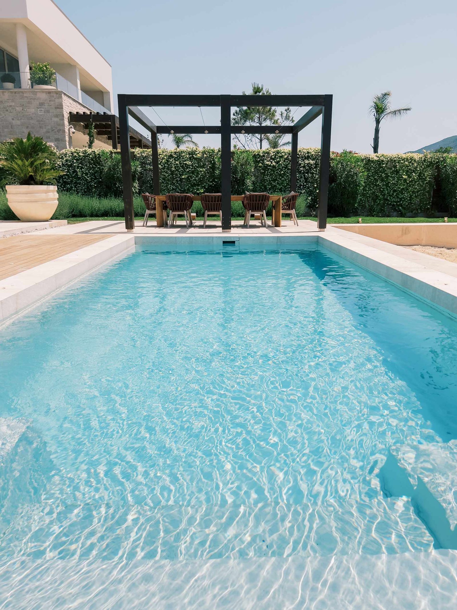 Piscine rectangulaire prolongée par une pergola en bois et un coin repas, pisciniste à Brie-Comte-Robert